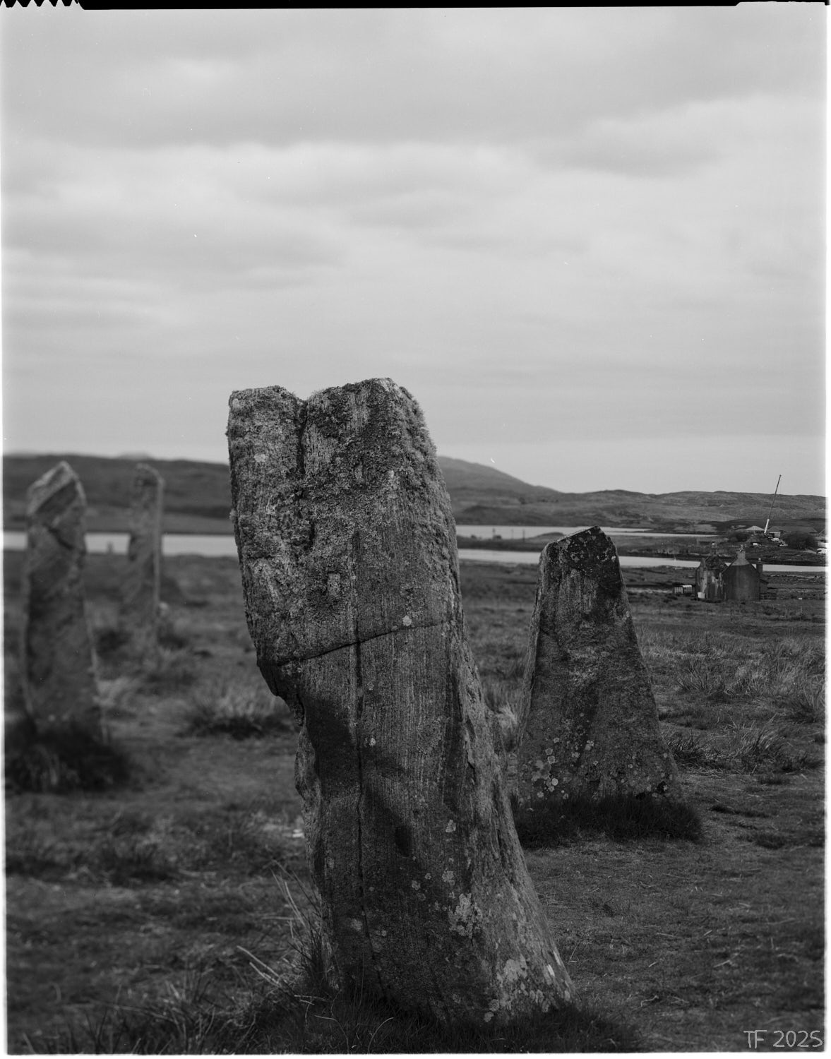 image of standing stones, derelict house in mid ground, construction site with a crane in background