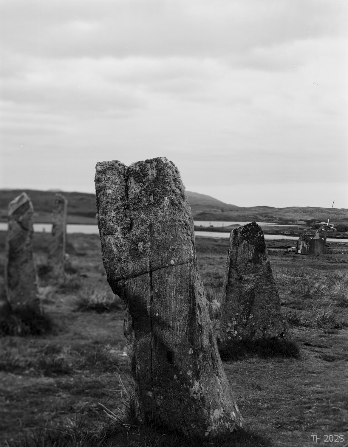 image of standing stones, derelict house in mid ground, construction site with a crane in background