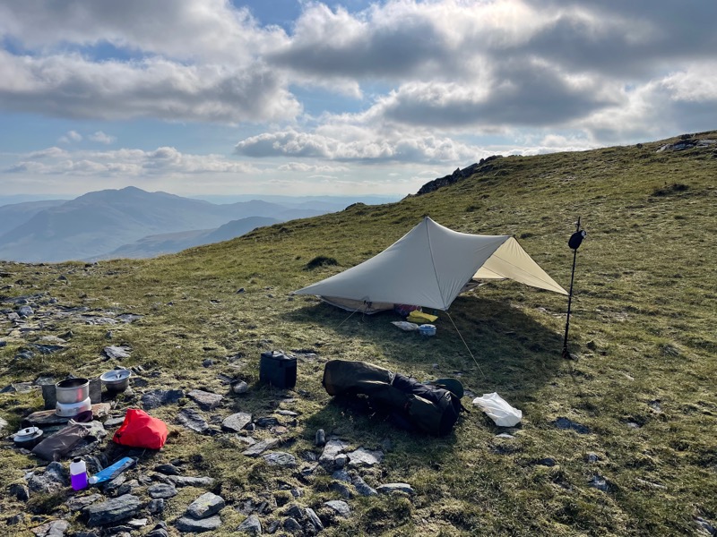 A tent and cooking equipment on a hillside