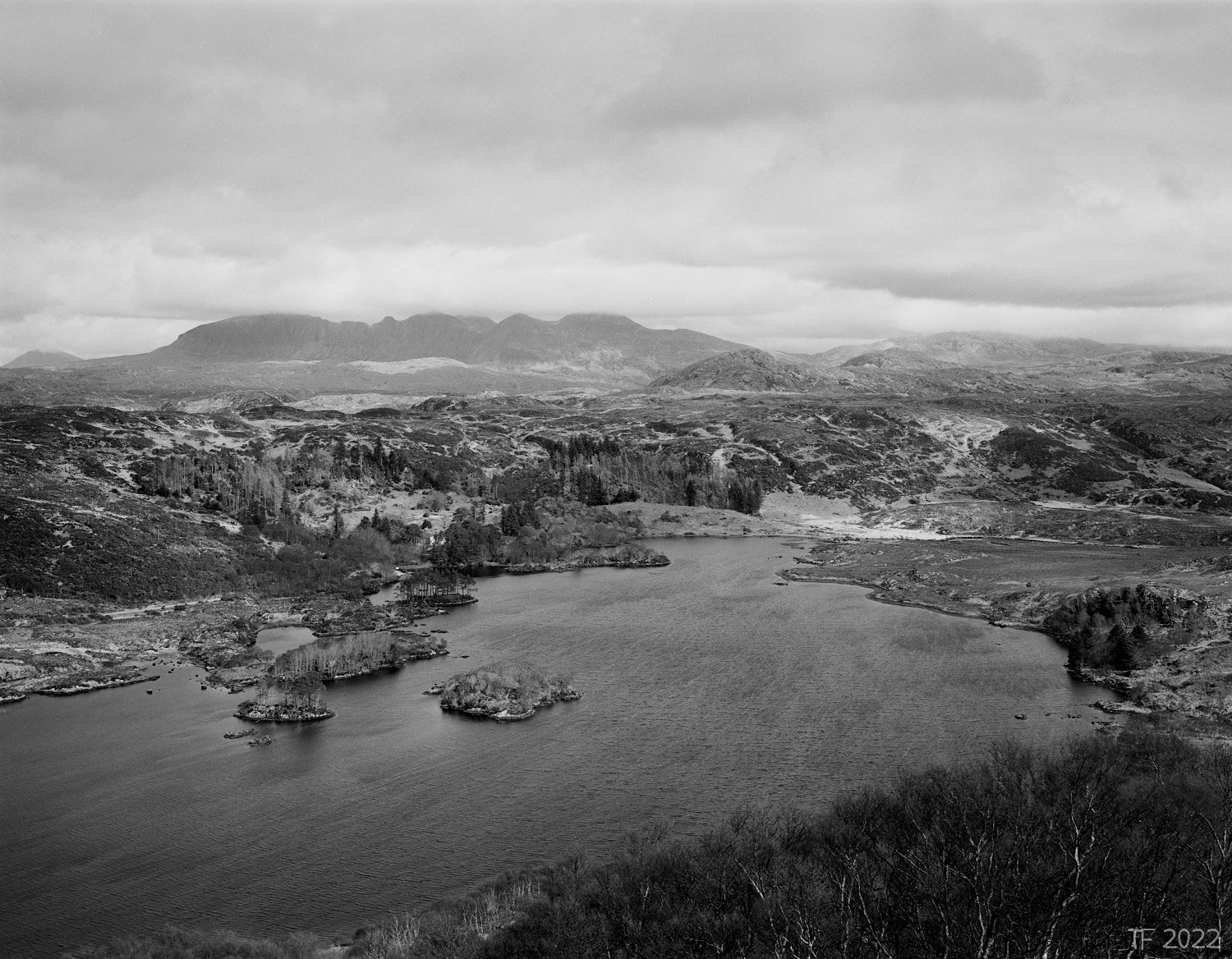 Black and white photograph of a wind swept Scottish loch with hills in the background
